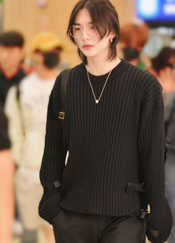 Stray Kids' Hyunjin making a statement at the airport, wearing a dramatic long coat that showcases his romantic and powerful style.