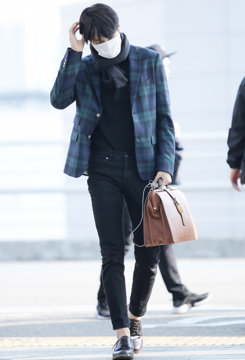 EXO's Kai confidently walking through the airport, modeling a bold, high-fashion look as the 'Human Gucci'.