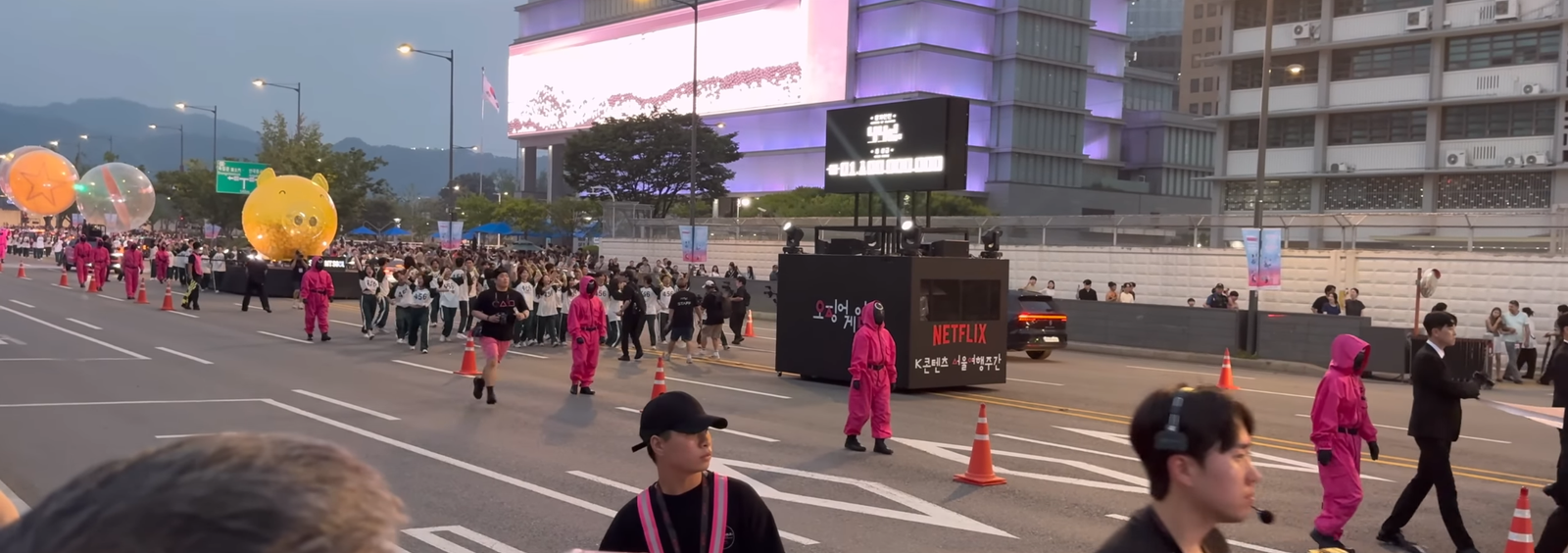 A crowd of people in Seoul, gathered around a Squid Game themed event, with faces showing a mix of excitement and curiosity, illustrating the cultural phenomenon.